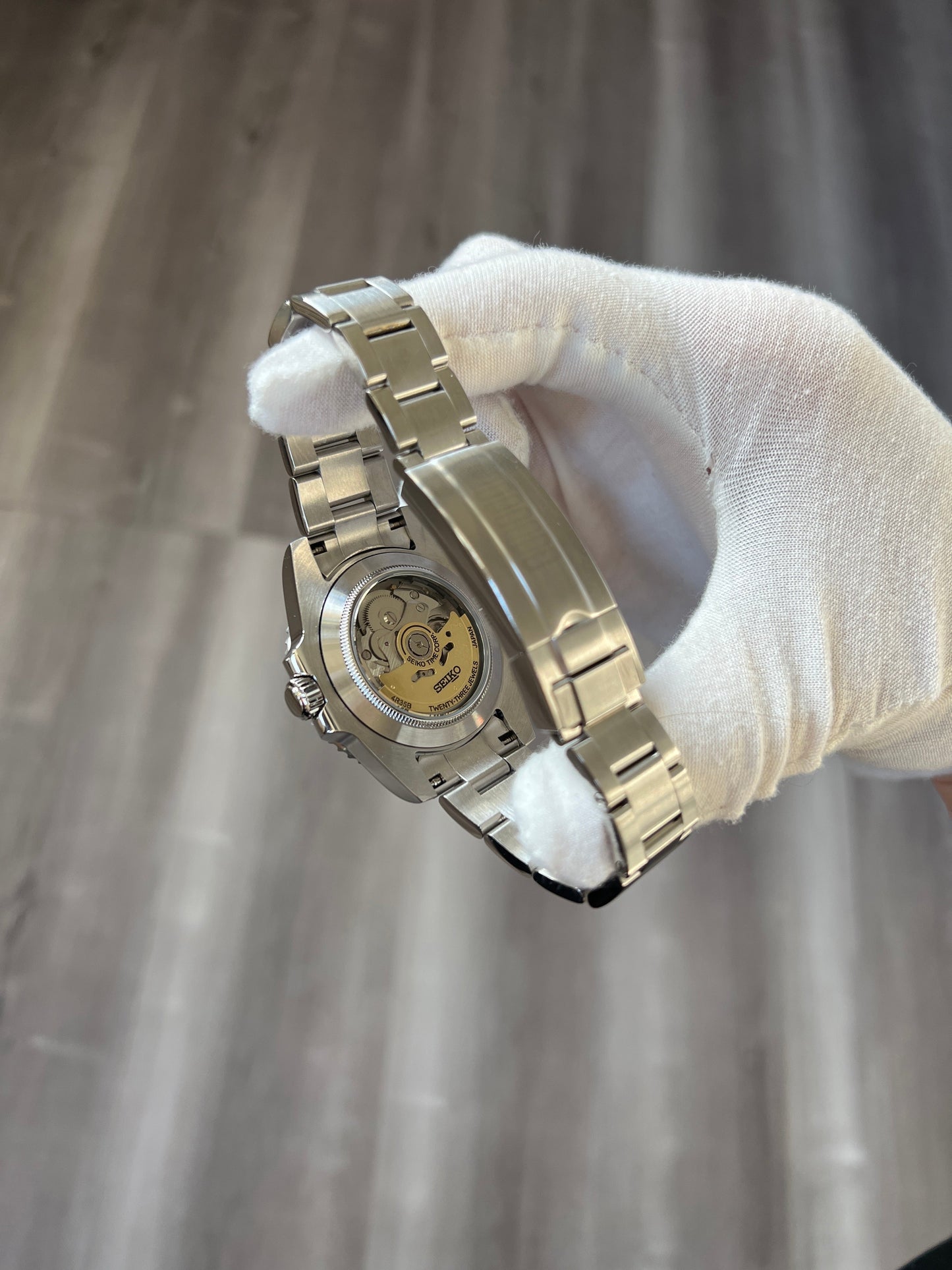 Submariner (Black) Seiko NH35 automatic mod watch. A caseback detail showing the mechanical movement of the watch held by a gloved hand.