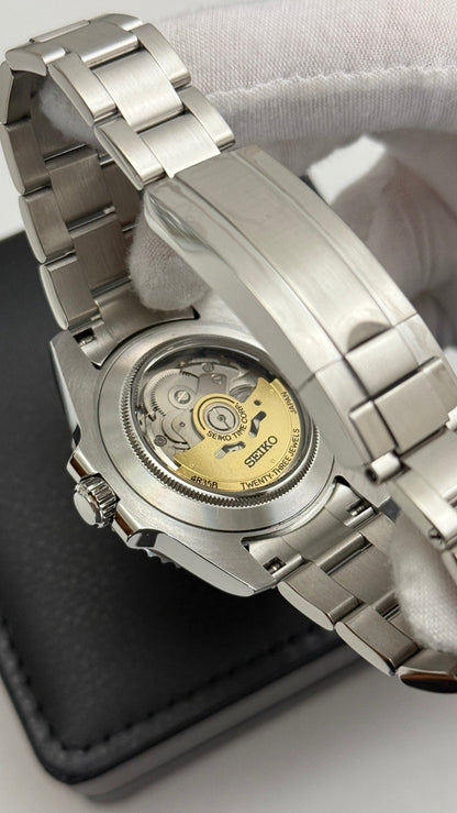 Submariner (Blue) Seiko NH35 automatic mod watch. A caseback view showing the internal mechanical movement of a watch with a silver metal link bracelet.