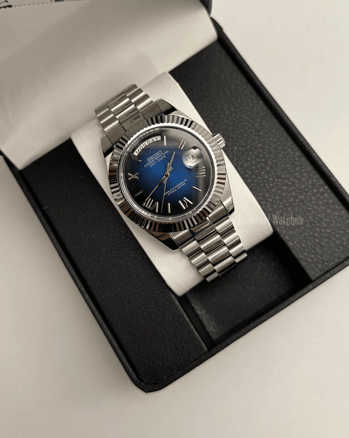 Day-Date (Blue Roman) Japanese automatic mod watch. A watch in a box with a blue dial and silver fluted bezel on a silver metal bracelet.