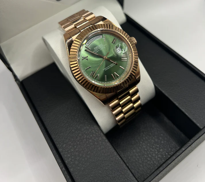 Day-Date (Rose Gold, Green) Japanese automatic mod watch. A full watch shot shows the rose gold watch with a green dial resting on a white pillow inside a box.