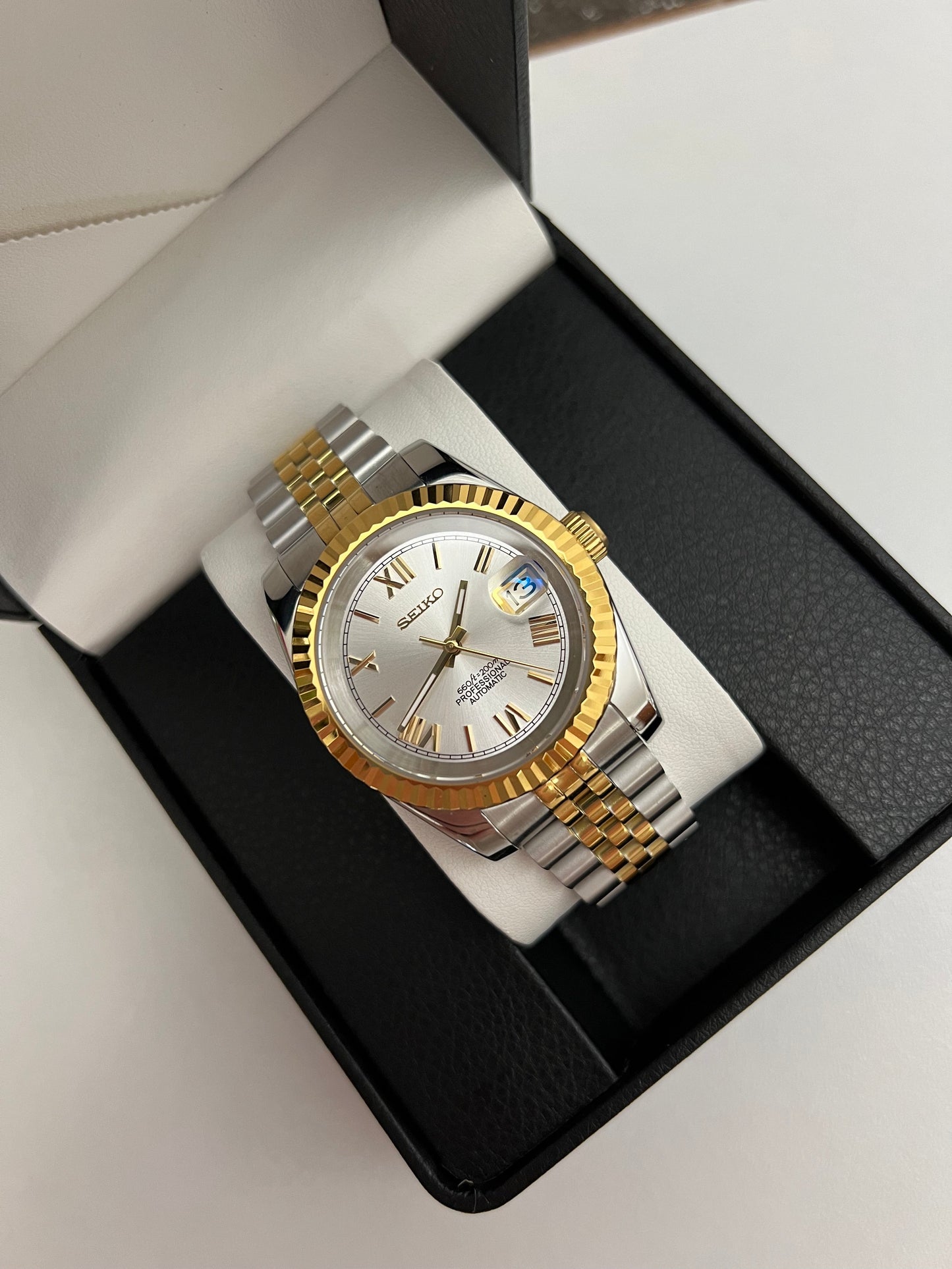 Datejust (Two-Tone White Roman) Seiko NH35 automatic mod watch. A silver dial watch with a gold fluted bezel and two tone jubilee bracelet sits inside a black box.