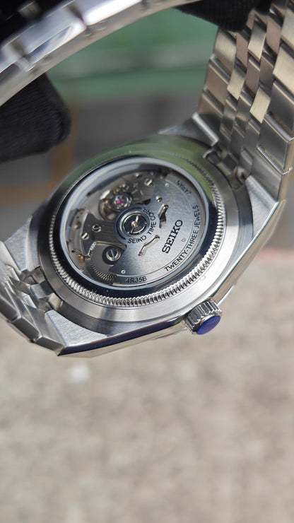 Land-Dweller (Tiffany) Seiko NH35 automatic mod watch. The silver caseback of a watch showing the internal mechanical movement and a clear exhibition window.