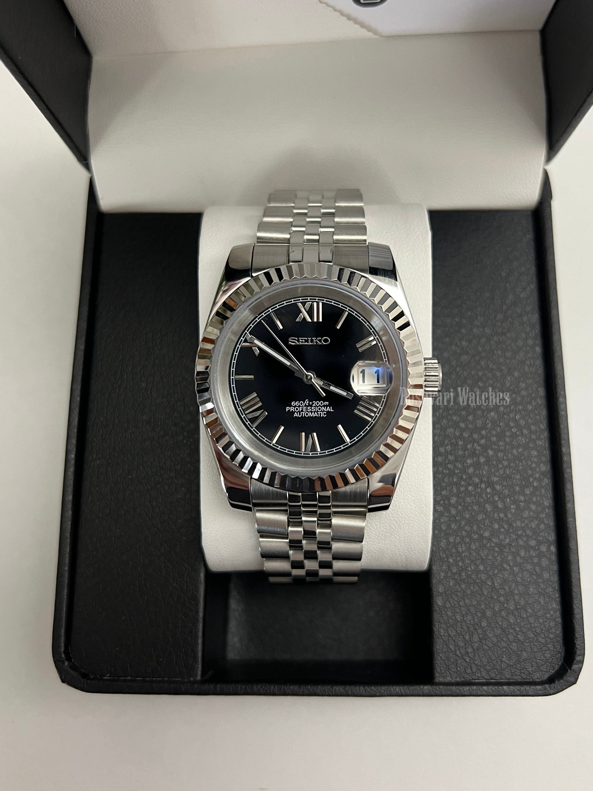 Datejust (Black Roman) Seiko NH35 automatic mod watch. A black dial watch with a silver fluted bezel and jubilee bracelet inside a box in a high angle shot.