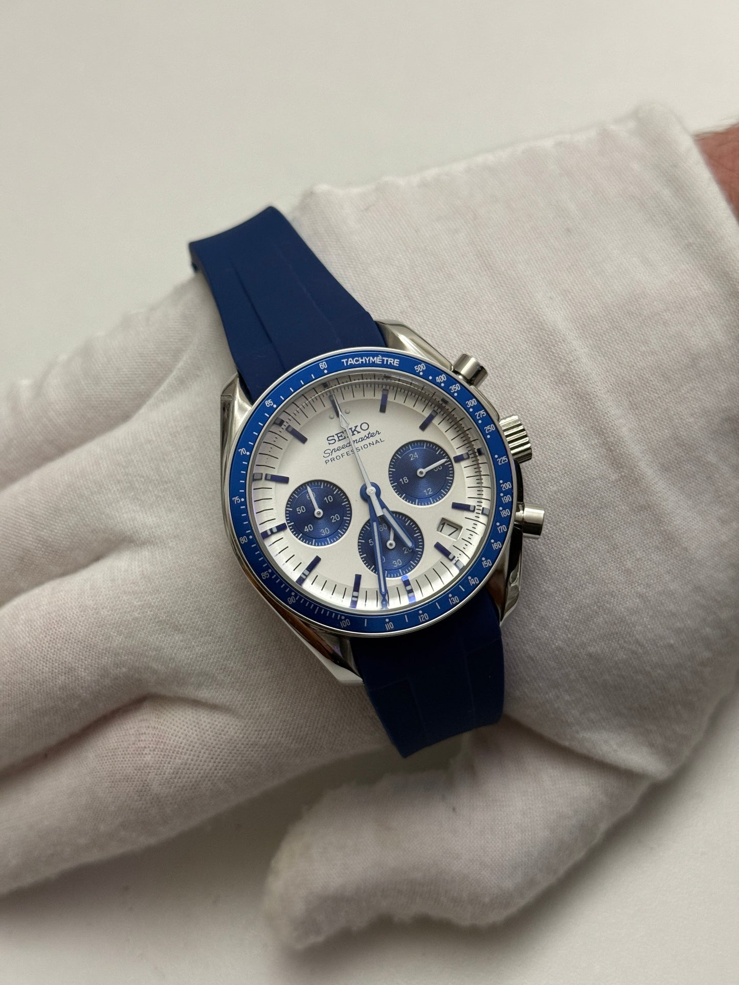 Speedmaster (Blue) Seiko VK63 meca-quartz chronograph mod watch. A full watch shot showing a white dial with blue sub dials and a blue bezel on a blue rubber strap.