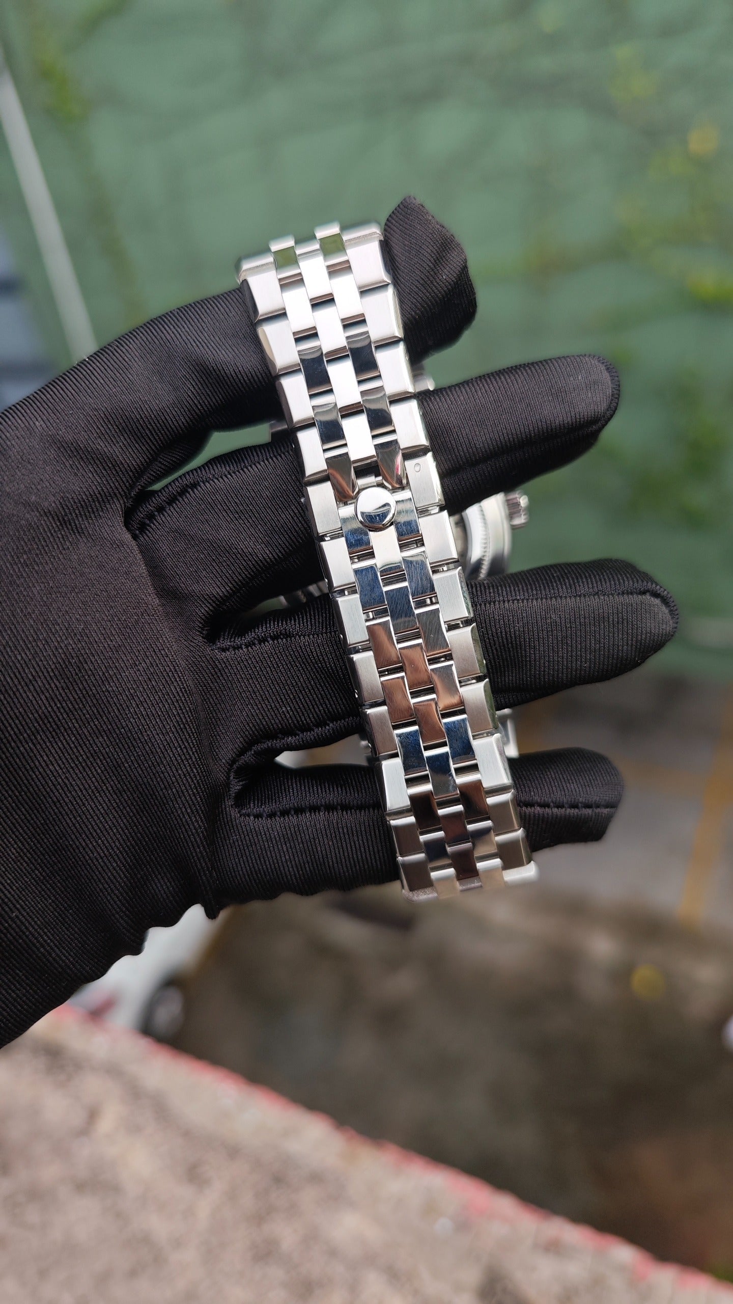 Land-Dweller Seiko NH35 automatic mod watch. A view of the metal link bracelet and clasp of the silver watch held by a gloved hand.