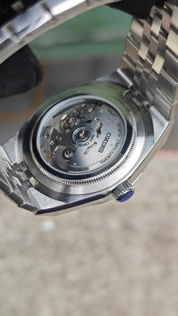 Land-Dweller Seiko NH35 automatic mod watch. A close up view of the clear caseback showing the mechanical movement of the silver watch.