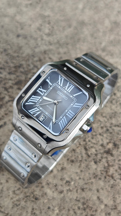 Santos (Graphite) Seiko NH35 automatic mod watch. A high angle full watch shot showing a grey dial with a black bezel and a metal link bracelet.