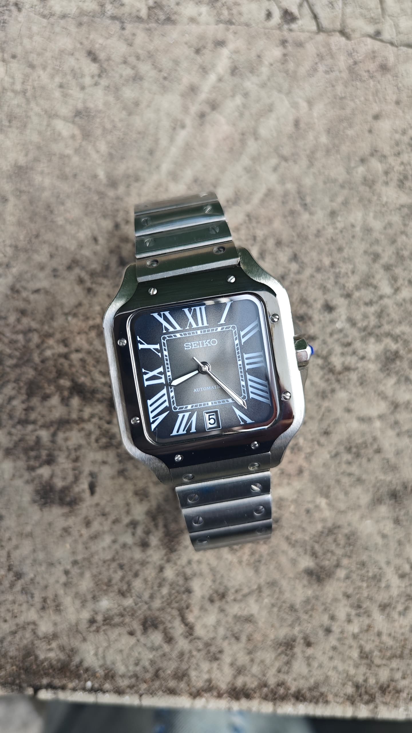 Santos (Graphite) Seiko NH35 automatic mod watch. A top down full watch shot showing a grey dial with a black bezel and a metal link bracelet.
