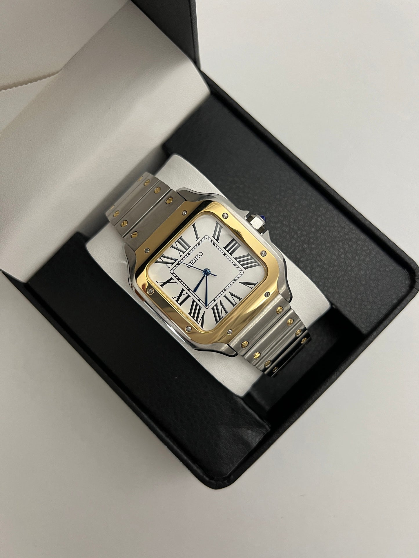Santos (Two-Tone Gold) Seiko NH35 automatic mod watch. A watch in a box showing a white dial with a gold bezel and a silver and gold metal link bracelet.