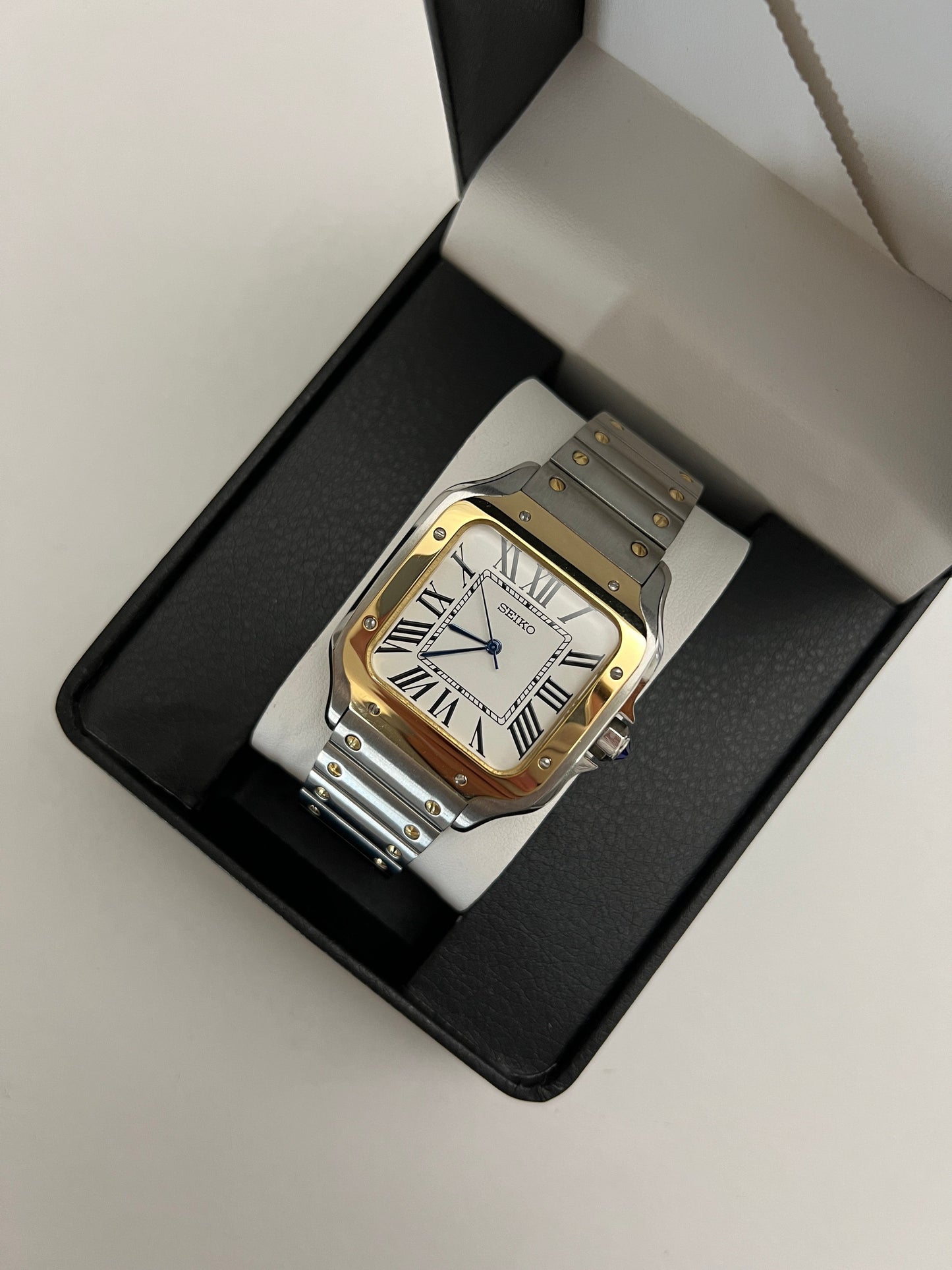 Santos (Two-Tone Gold) Seiko NH35 automatic mod watch. A watch in a box showing a white dial with a gold bezel and a silver and gold metal link bracelet.