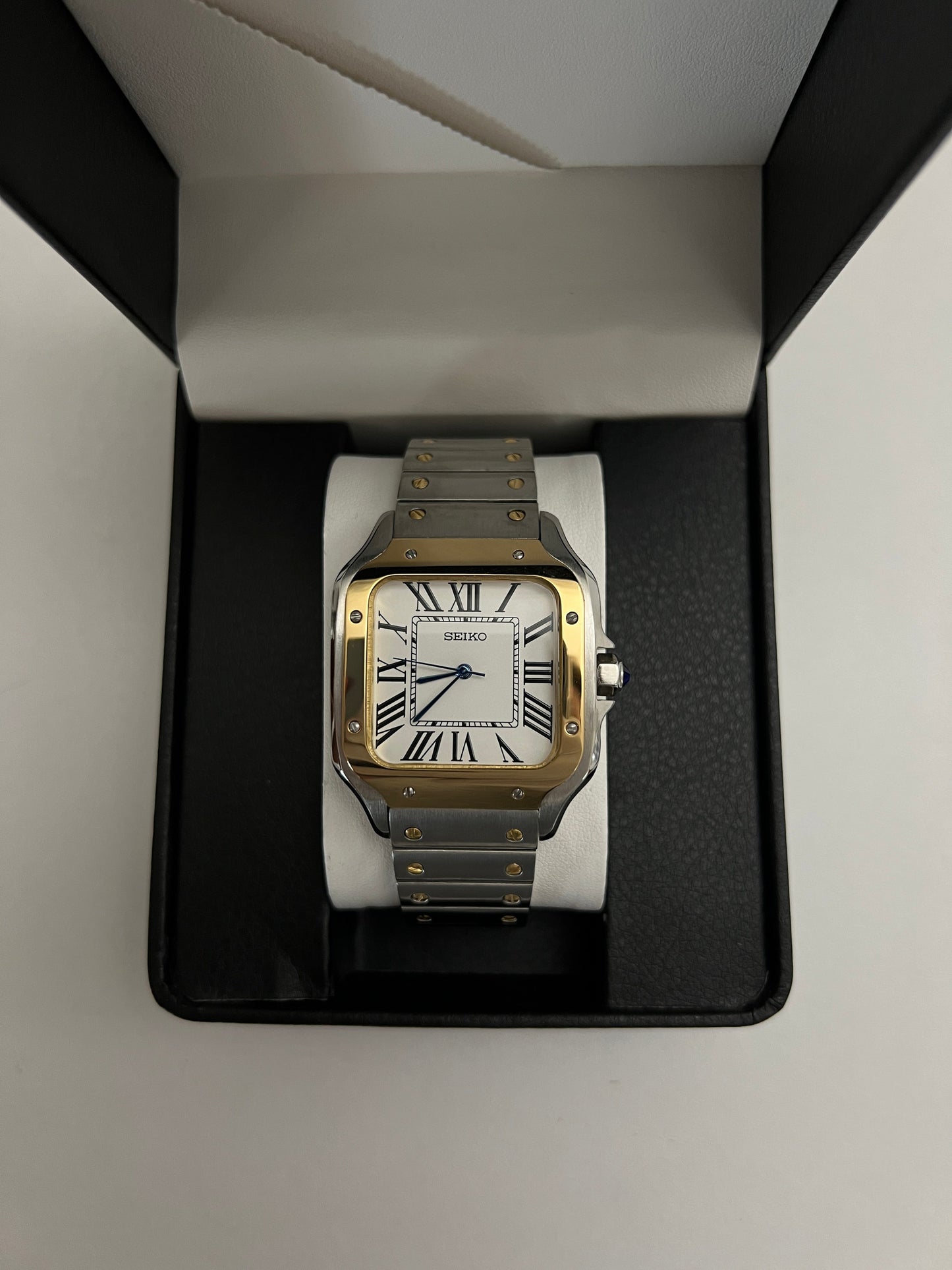Santos (Two-Tone Gold) Seiko NH35 automatic mod watch. A watch in a box showing a white dial with a gold bezel and a silver and gold metal link bracelet.
